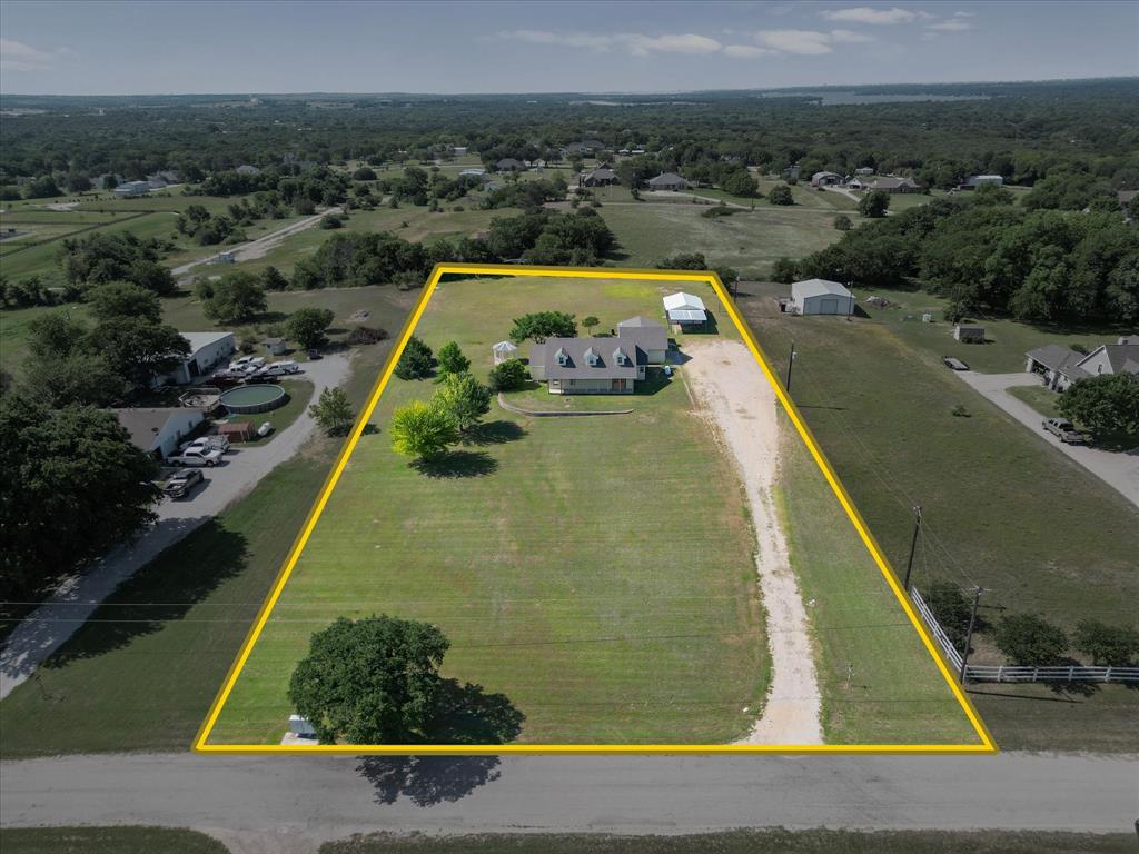 289 County Road 4655 Rhome, TX 76078 - Photo 28 of 34 Expansive lot featuring a single-story residence with a gabled roof and dormer windows, a detached metal outbuilding, and a second covered structure