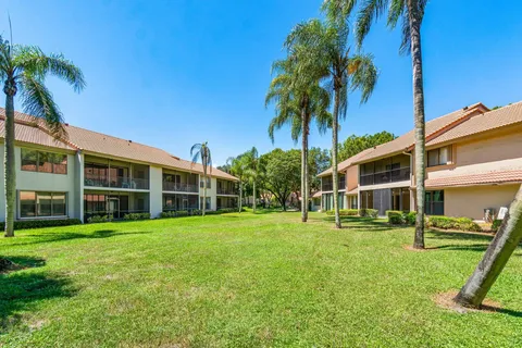 a yellow house with a yard and palm trees