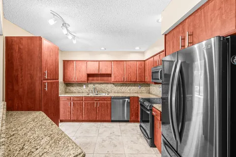 a kitchen with stainless steel appliances granite countertop wooden cabinets a stove top oven a sink and dishwasher