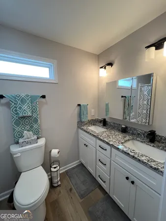 a bathroom with a granite countertop toilet a sink and a mirror
