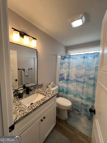 a bathroom with a granite countertop sink a toilet a mirror and shower