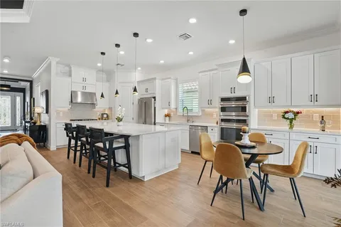 a kitchen with kitchen island a dining table chairs cabinets and stainless steel appliances
