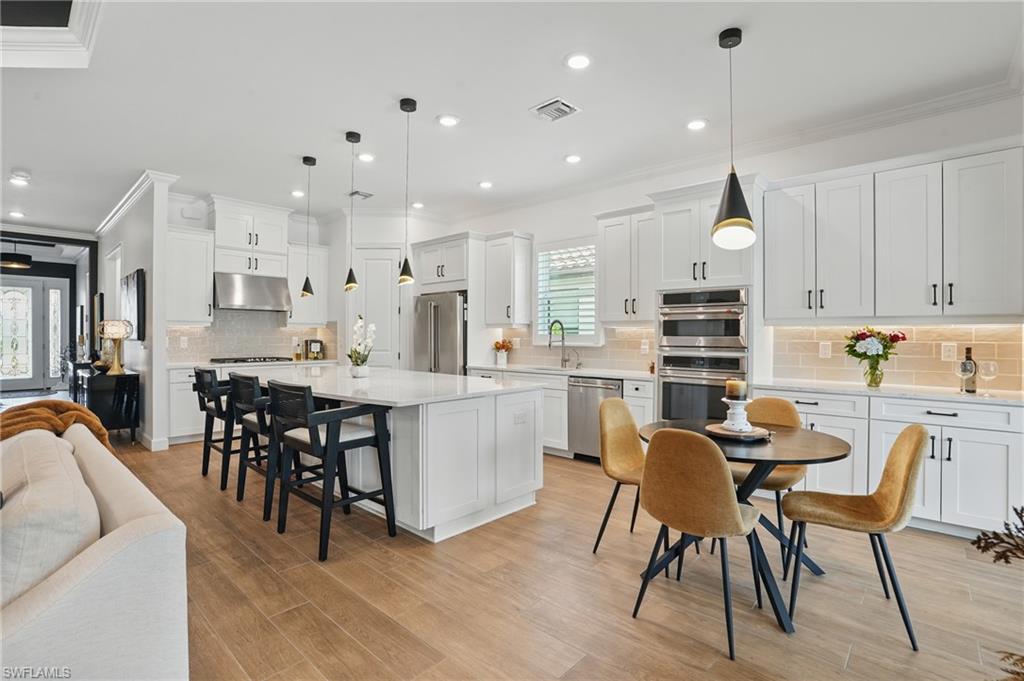 17467 Caravita Lane Fort Myers, FL 33913 - Photo 13 of 50 a kitchen with kitchen island a dining table chairs cabinets and stainless steel appliances