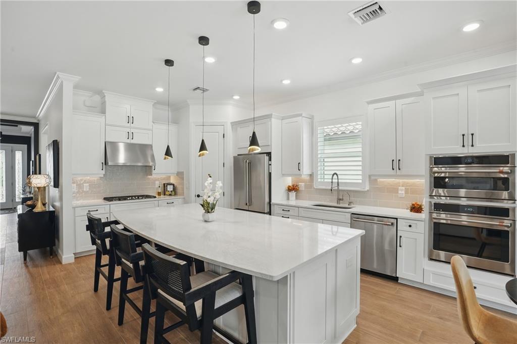 17467 Caravita Lane Fort Myers, FL 33913 - Photo 16 of 50 a kitchen with stainless steel appliances kitchen island granite countertop a table chairs microwave and cabinets