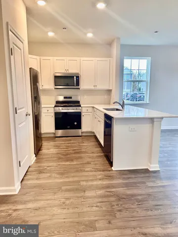 a kitchen with granite countertop a refrigerator and a stove top oven