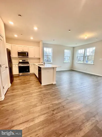 a view of kitchen with microwave a stove and wooden floor