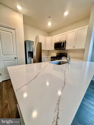 a kitchen with stainless steel appliances a refrigerator a sink a stove a microwave a center island and furniture