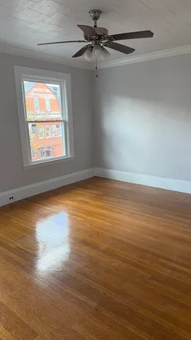 an empty room with wooden floor fan and windows