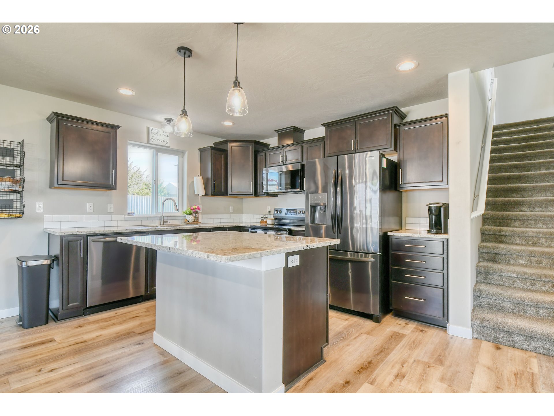 233 East Jefferson Street Athena, OR 97813 - Photo 14 of 36 a kitchen with stainless steel appliances kitchen island granite countertop a refrigerator a stove and a sink with wooden floor