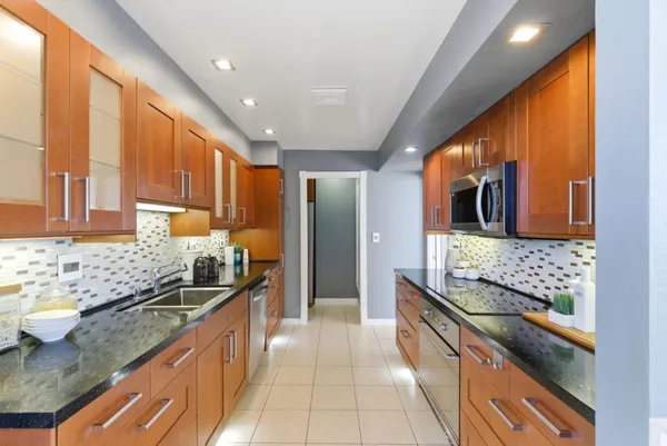 a large kitchen with stainless steel appliances kitchen island granite countertop a sink and cabinets