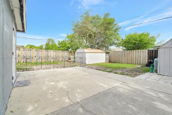 a view of a backyard with large trees and wooden fence