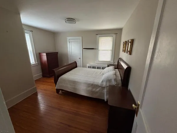 a bedroom with a bed window and wooden floor