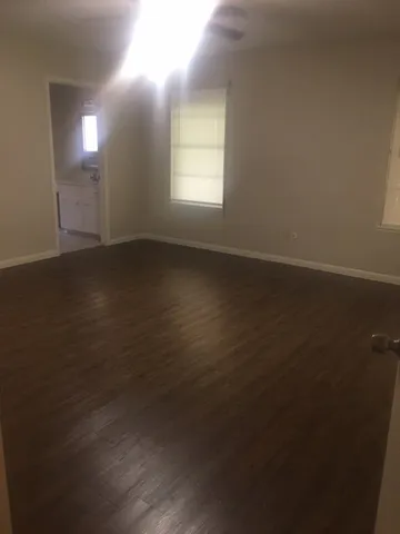 an empty room with wooden floor and windows in it