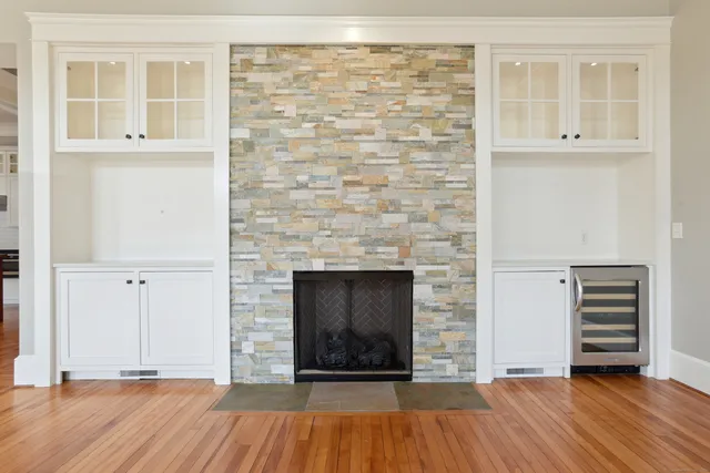 an empty room with wooden floor a fireplace and windows