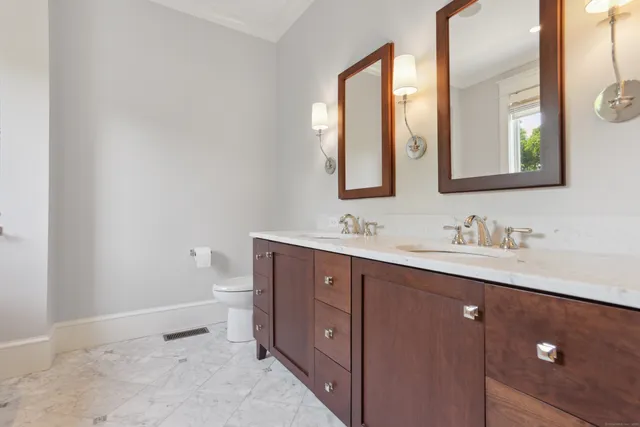 a bathroom with a double vanity sink and mirror with toilet