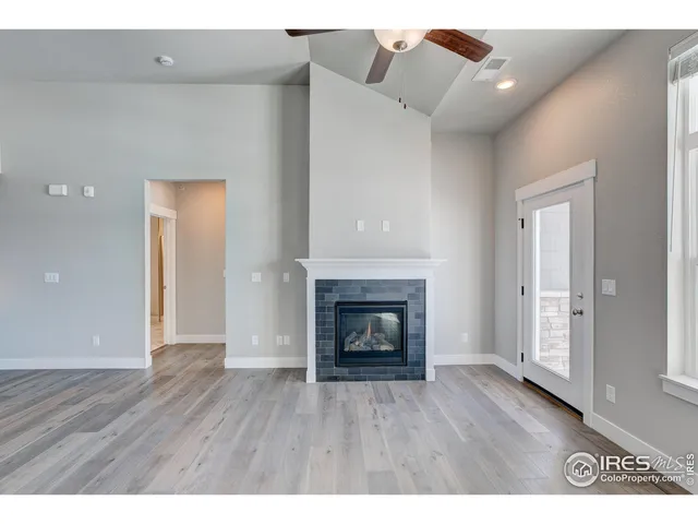a view of an empty room with wooden floor fireplace and a window
