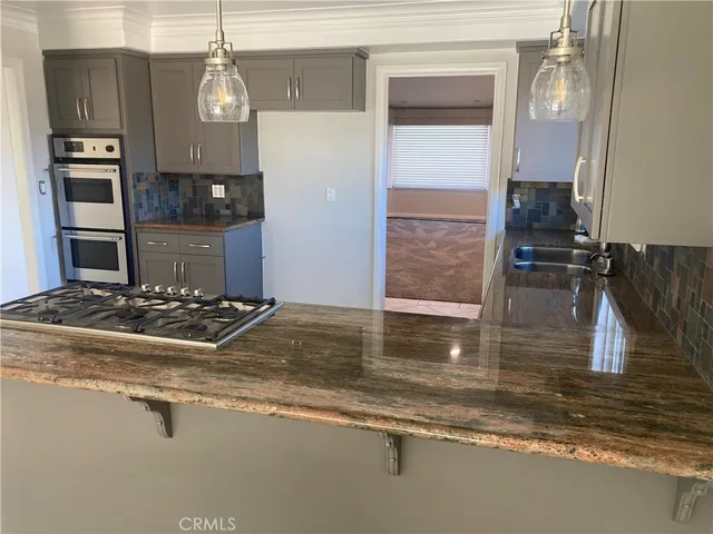 a view of a kitchen with stainless steel appliances granite countertop a stove and a refrigerator