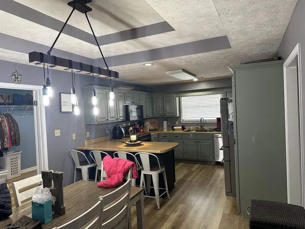 a kitchen with a stove a refrigerator and a dining table with wooden floor