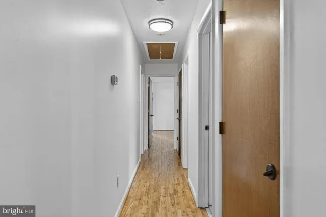 a view of an empty room with wooden floor and a ceiling fan
