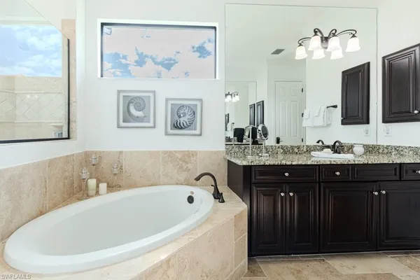 a bathroom with a granite countertop sink a mirror and a bathtub