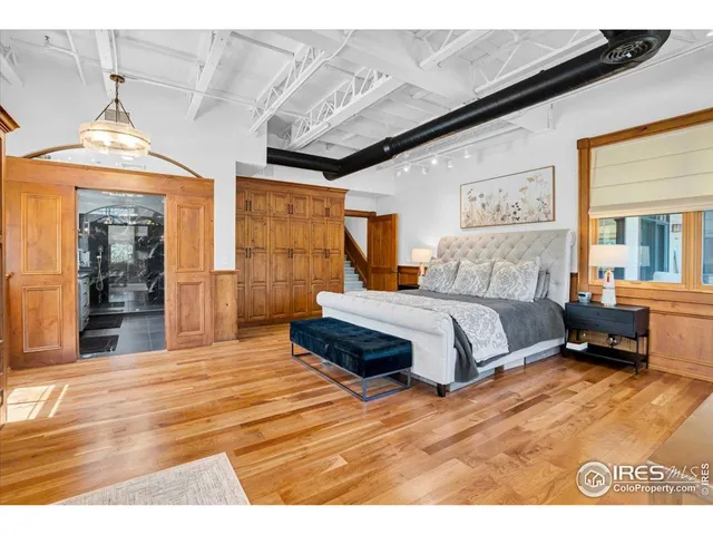 a spacious bedroom with a bed a dresser and large windows