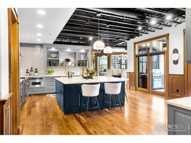 a living room with stainless steel appliances kitchen island granite countertop a large kitchen view and a wooden floors