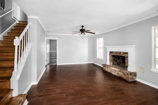 an empty room with wooden floor fireplace and windows