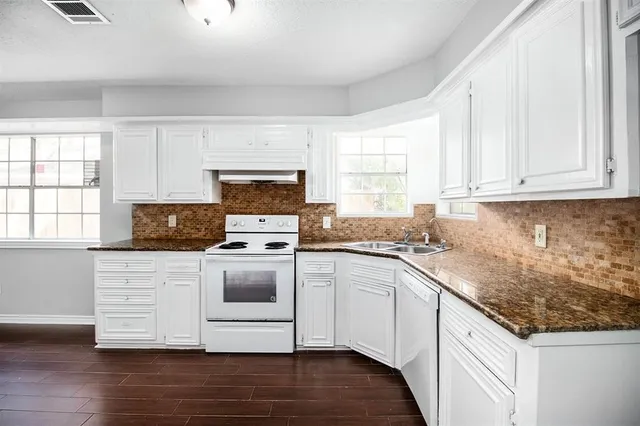 a kitchen with stainless steel appliances granite countertop a stove a sink and white cabinets