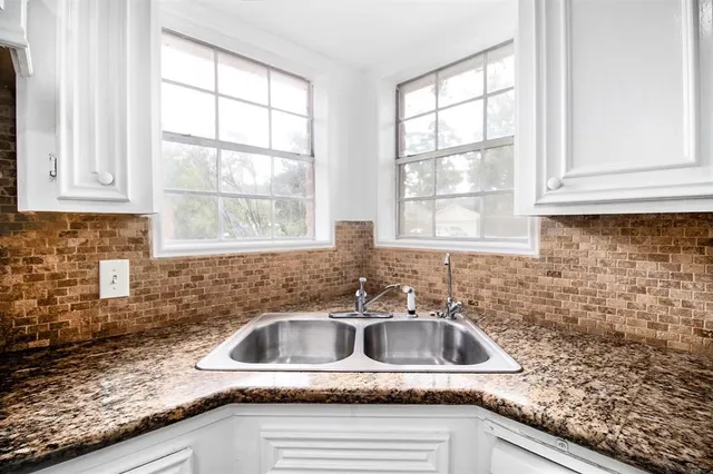 a kitchen with granite countertop a sink window and cabinets
