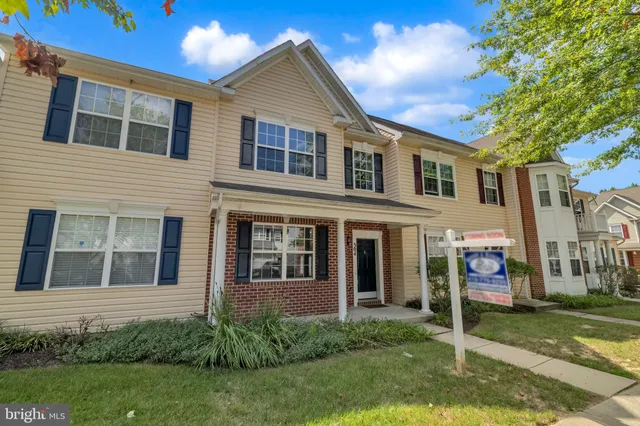 a view of a yard in front of a brick house with a large windows