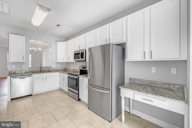 a kitchen with granite countertop white cabinets and stainless steel appliances