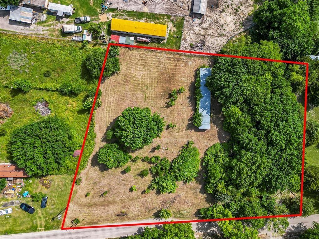 121 Wickliffe Road Ferris, TX 75125 - Photo 5 of 10 Expansive parcel featuring a mix of cleared land and mature trees, with a structure featuring a metal roof