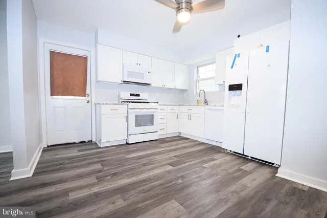 a kitchen with granite countertop a stove a sink and a refrigerator
