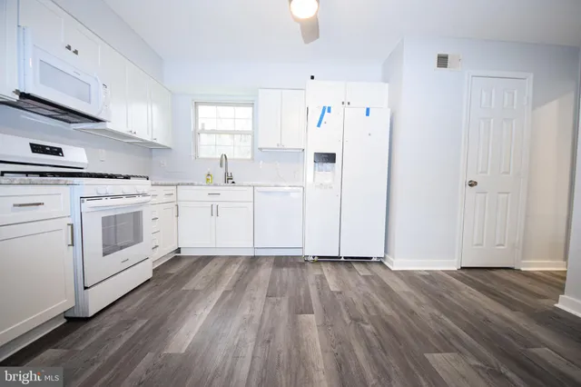 a kitchen with white cabinets and white appliances