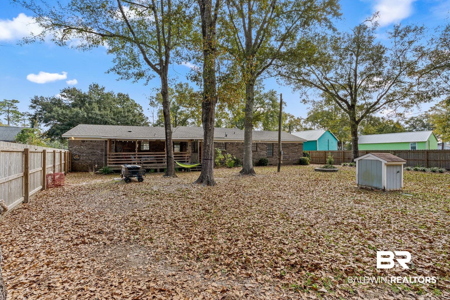 6801 Piney Woods Road Foley, AL 36535 - Photo 66 of 74 Back of property featuring a fenced backyard, brick siding, and a shed