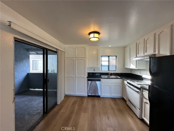 a kitchen with granite countertop a stove a sink and a refrigerator