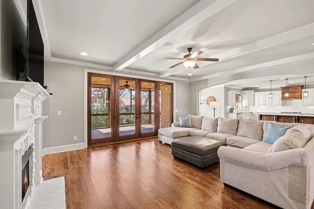 a living room with a fireplace furniture a flat screen tv and a floor to ceiling window