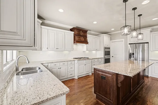 a large kitchen with stainless steel appliances granite countertop a lot of counter space and wooden floors