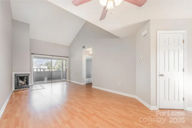 a view of an empty room with window and wooden floor