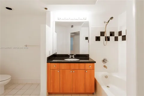 a bathroom with a granite countertop sink a toilet and bathtub