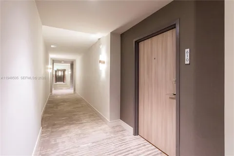 a view of a hallway with wooden floor and a bathroom
