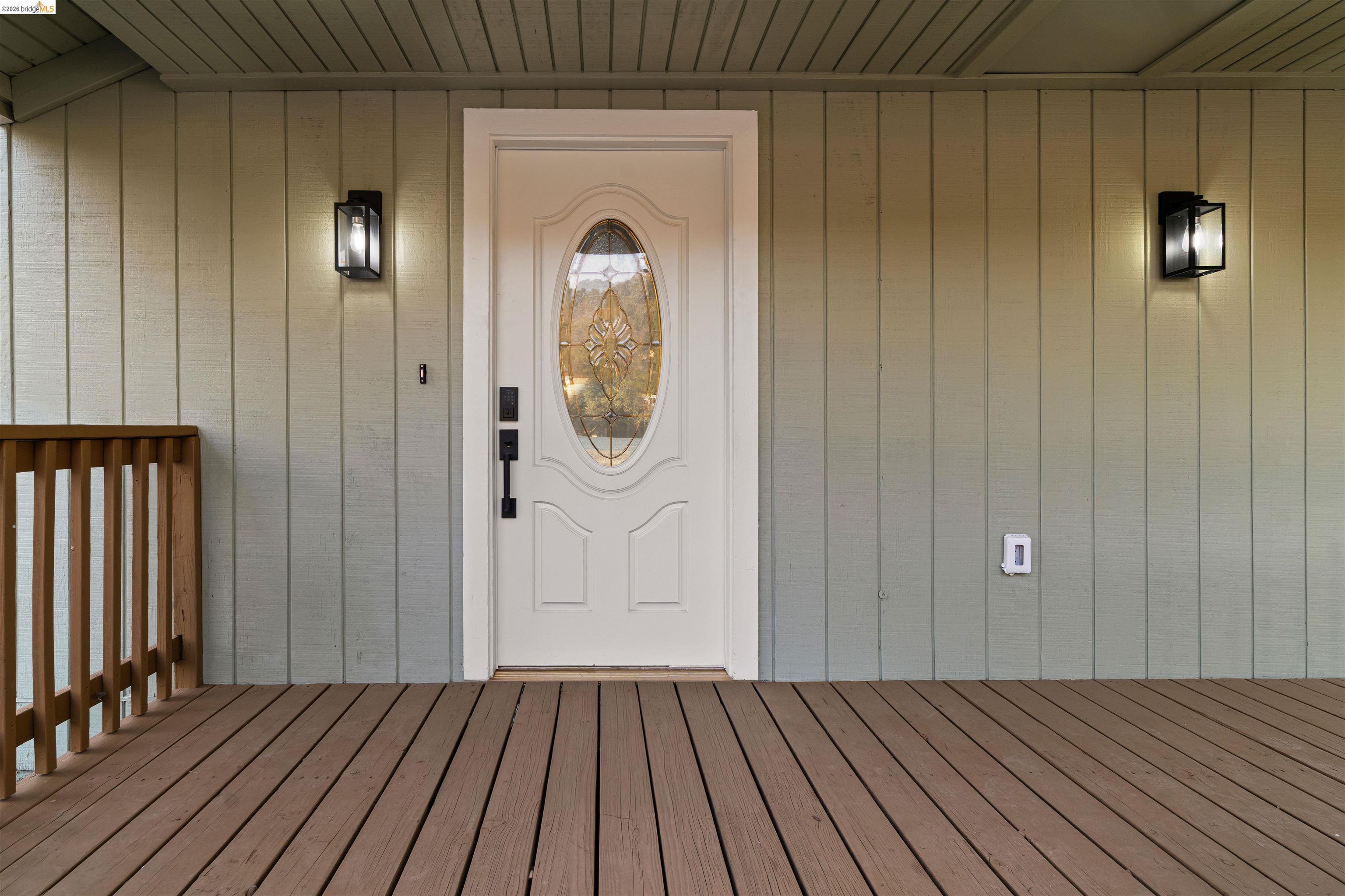19676 Rawhide Road Sonora, CA 95370 - Photo 8 of 67 Front entry featuring a white door with decorative glass, two exterior sconces, and a wood-finish deck