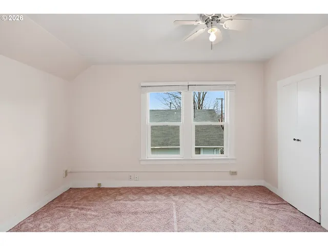 an empty room with chandelier fan and windows