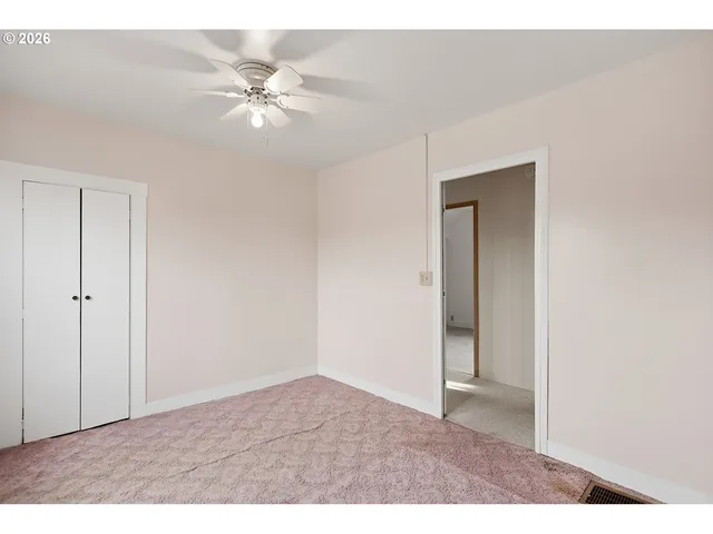 a view of an empty room and chandelier fan