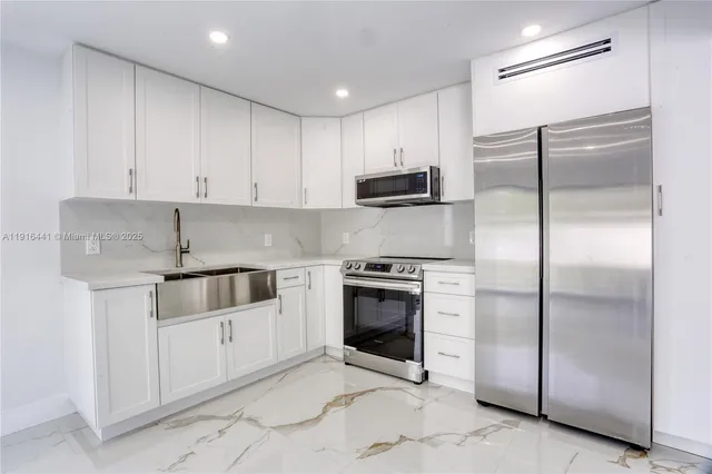 a kitchen with stainless steel appliances kitchen island granite countertop a refrigerator a stove and a sink with wooden floor