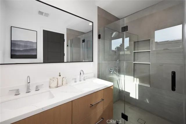 a bathroom with a double vanity sink mirror and shower