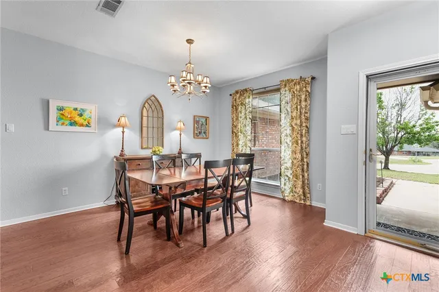 a view of a dining room with furniture a chandelier and wooden floor
