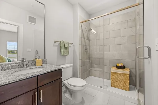a bathroom with a granite countertop sink a toilet and shower