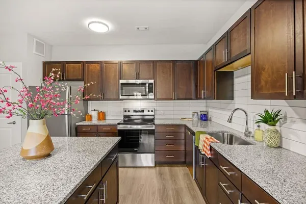 a kitchen with granite countertop a sink a counter top space appliances and cabinets