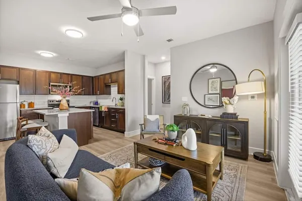 a living room with furniture a rug kitchen view and a chandelier